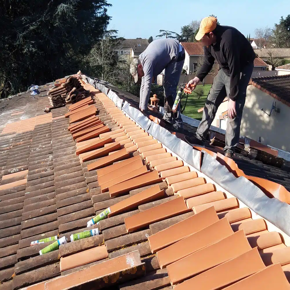Réfection de toiture en cours avec deux couvreurs sur le rampant à Villeneuve-Tolosane