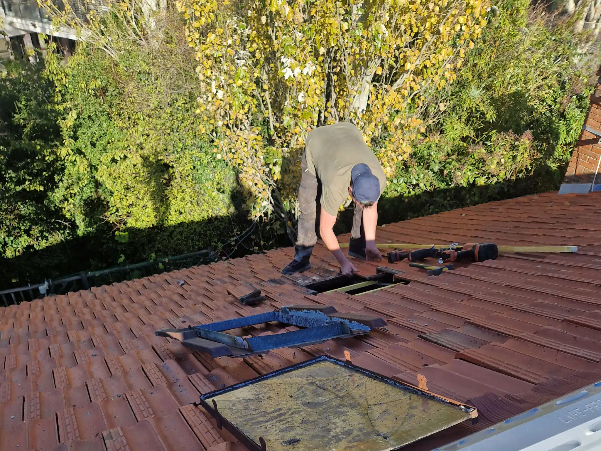 Couvreur agenouillé sur une toiture en cours de réfection à Salies-du-Salat