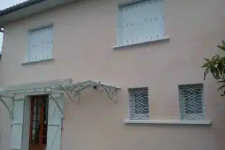 Façade rose pâle et treille métallique après ravalemen